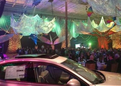 A car exhibit at a fundraiser with hanging colorful decorations and fairy lights.