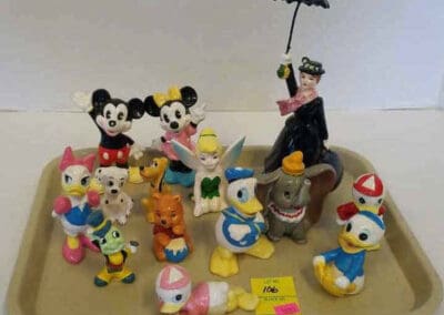 A collection of vintage Disney figurines, including characters like Mickey Mouse, Donald Duck, and Dumbo, displayed on a tray.