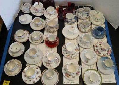 Assorted vintage tea cups and saucers displayed for auction on a table.