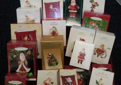 A display of various Hallmark Santa Claus-themed Christmas ornaments in their original boxes on a table.