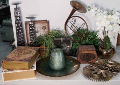Assorted vintage items up for auction, including books, a metal sculpture, a horn, and decorative plants on a display table.