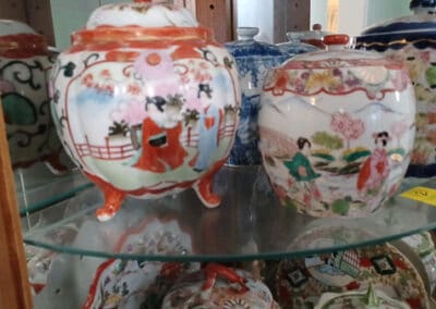 Assortment of colorful, ornately decorated ceramic pots displayed on a glass shelf.