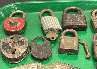 Assorted old and rusty padlocks, some with keys, displayed on a green tray.