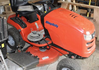 A red Simplicity lawn tractor parked in a garage.