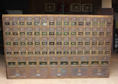 Large vintage postal box unit with numerous numbered compartments in a storage room.