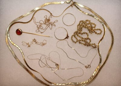 An assortment of gold jewelry pieces, including necklaces and earrings, displayed on a pale background.