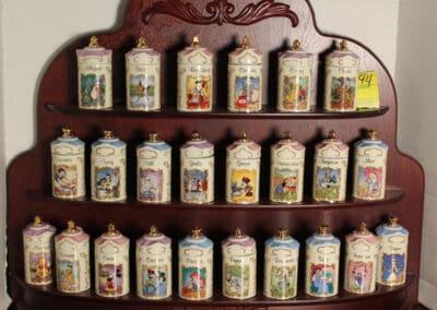 Wooden shelf with ornate ceramic spice jars labeled with spice names and illustrated characters.
