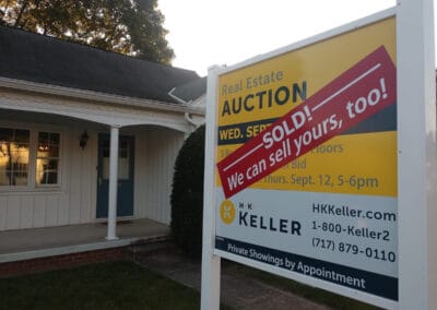 H. K. Keller auction sign stating "sold!" in front of a white house, with viewing times and contact information.