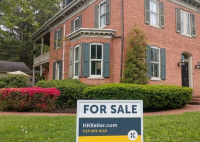 A two-story brick house with white trim and a "for sale" sign from H. K.. Keller in the front yard.