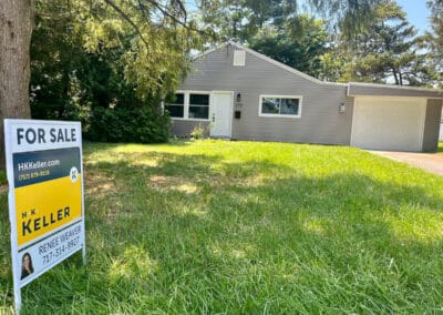 A single-story house with a gray exterior and attached garage for sale, featuring a front yard and an H.K. Keller sign.